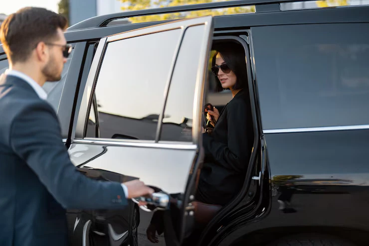Chauffeur opening taxi door for passenger at Stansted Airport